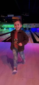 Jongentje lacht en loopt vrolijk bij kleurrijk verlichte bowlingbanen in Wima Schelle